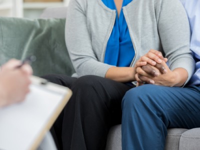 Couple holding hands during doctor visit.